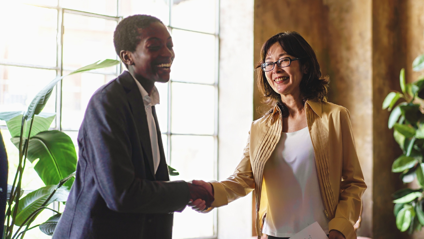Two co workers in the office shaking hands and smiling